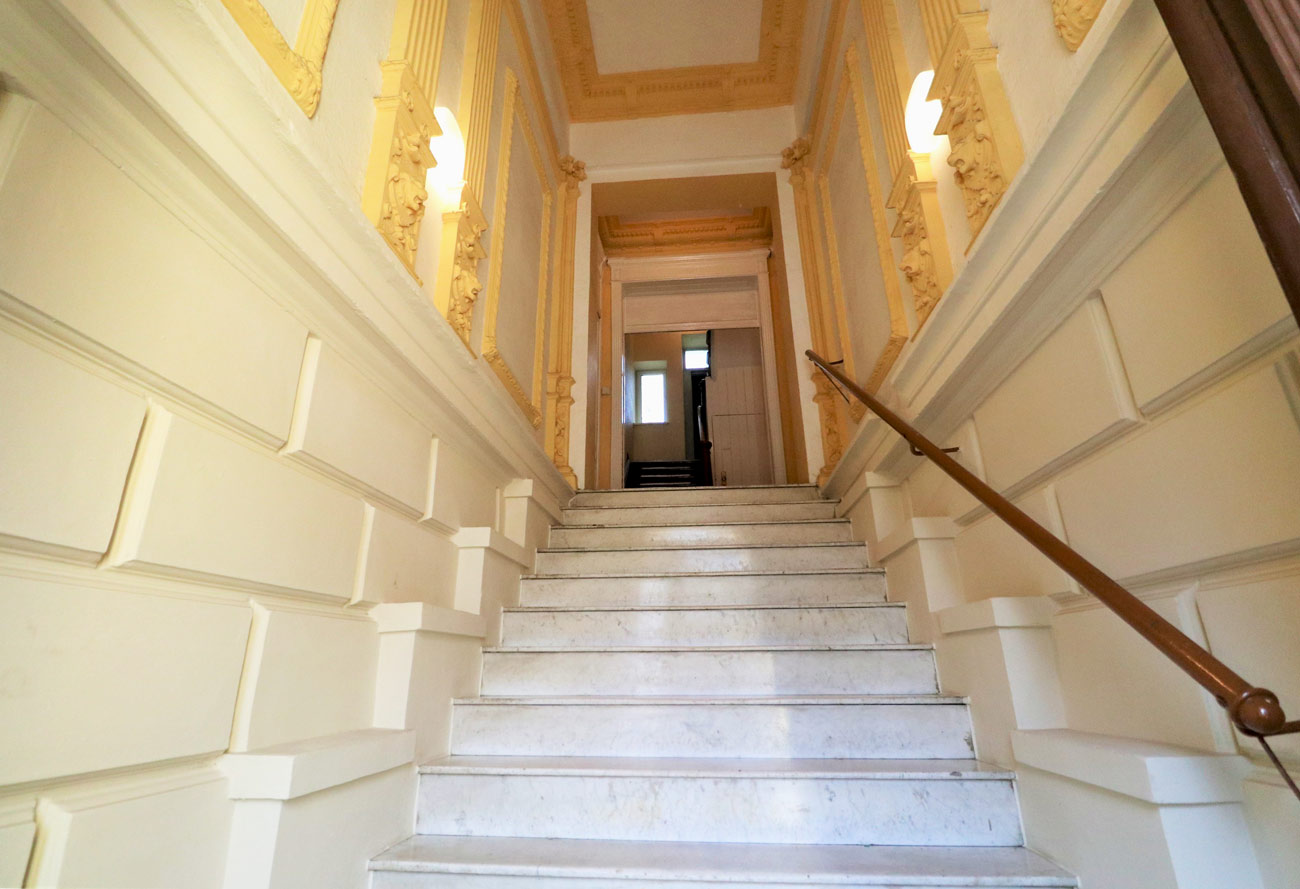 Stilvolles Altbau-Treppenhaus mit Marmorstufen und reich verzierter Wand- und Deckenarchitektur.