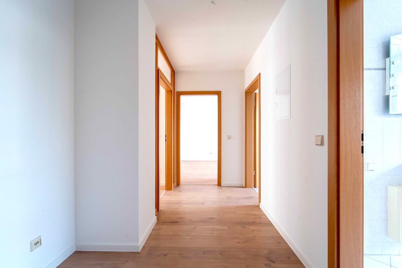 Heller Flur mit Holzfu&szlig;boden und T&uuml;ren mit Holzrahmen in moderner Wohnung, klar und freundlich gestaltet.